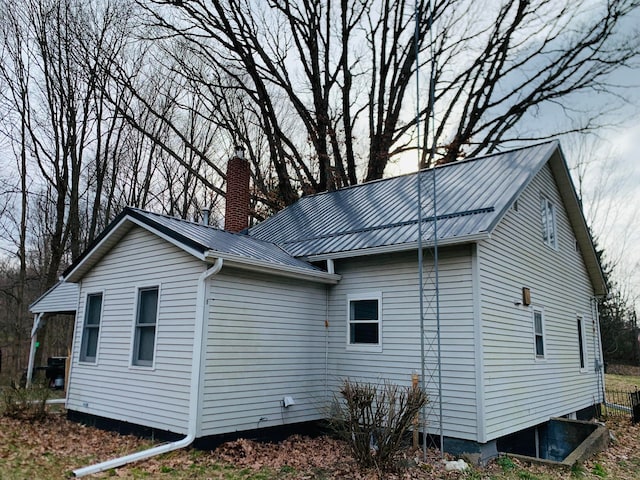 view of side of home featuring a chimney and metal roof