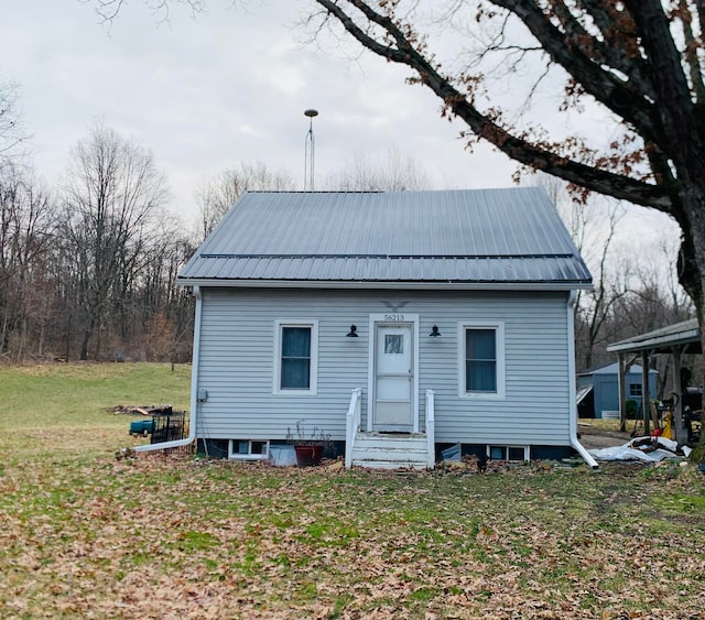 back of house with a yard, entry steps, and metal roof