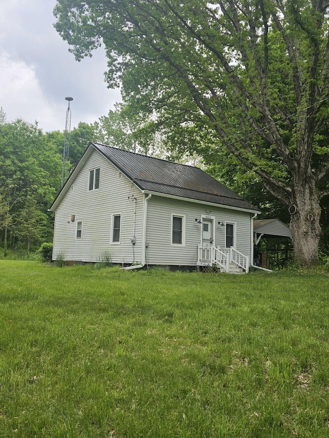 rear view of house featuring metal roof and a yard