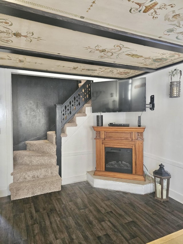 living area with a glass covered fireplace, dark wood finished floors, and stairway