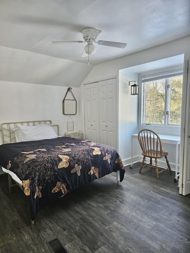 bedroom with ceiling fan, lofted ceiling, visible vents, a closet, and dark wood-style floors