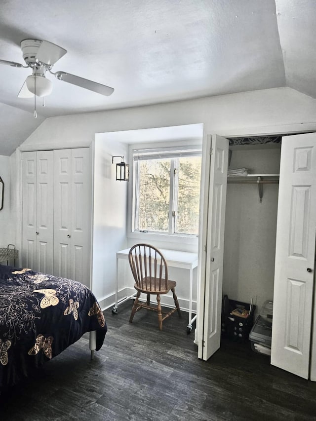 bedroom featuring vaulted ceiling, dark wood finished floors, two closets, and a ceiling fan