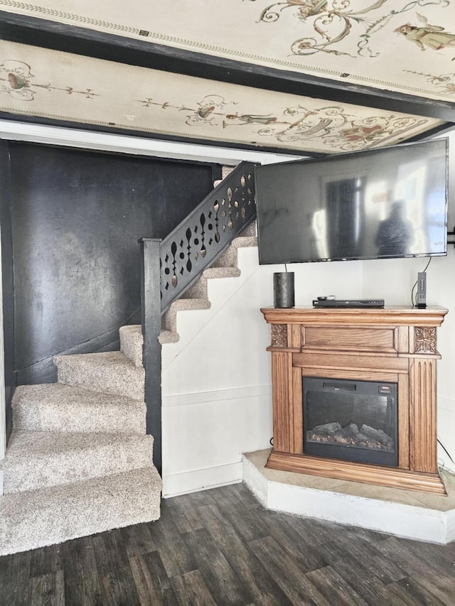 stairs with wood finished floors and a glass covered fireplace