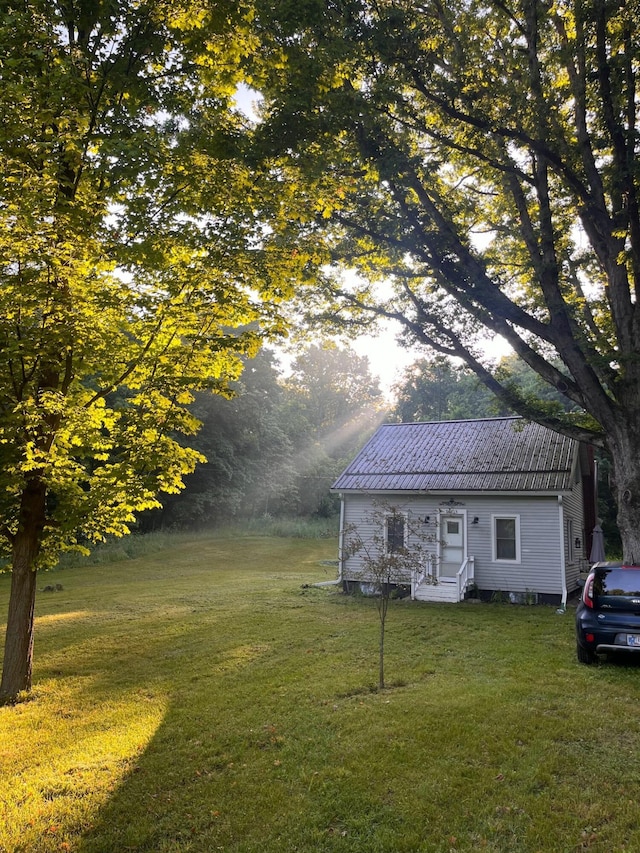 view of front of house with metal roof and a front lawn