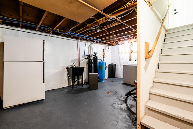 basement with white refrigerator and sink