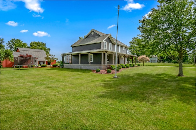 rear view of property with a trampoline and a yard