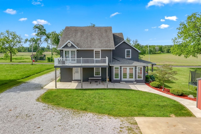 back of property featuring french doors, a balcony, a patio area, and a lawn