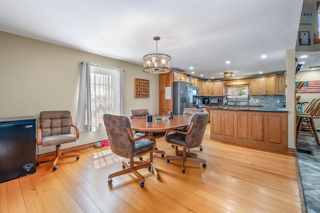 dining room with light wood-type flooring and an inviting chandelier