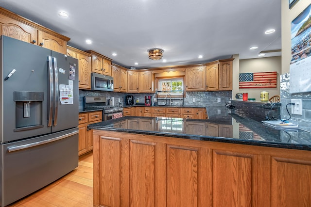 kitchen featuring sink, stainless steel appliances, kitchen peninsula, light hardwood / wood-style floors, and decorative backsplash