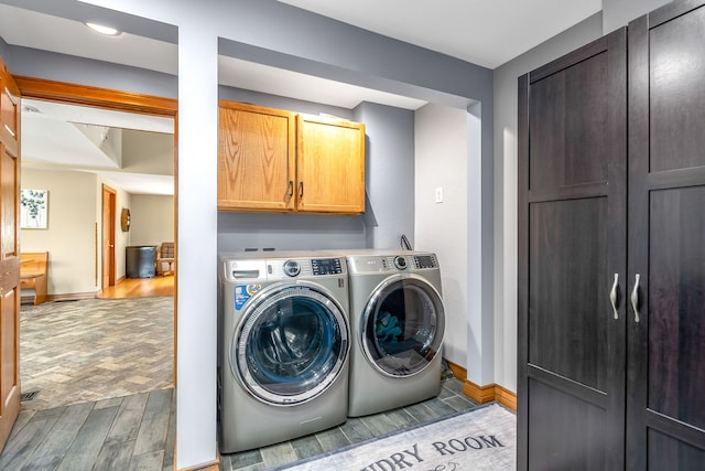 clothes washing area featuring cabinets, light wood-type flooring, and washer and clothes dryer