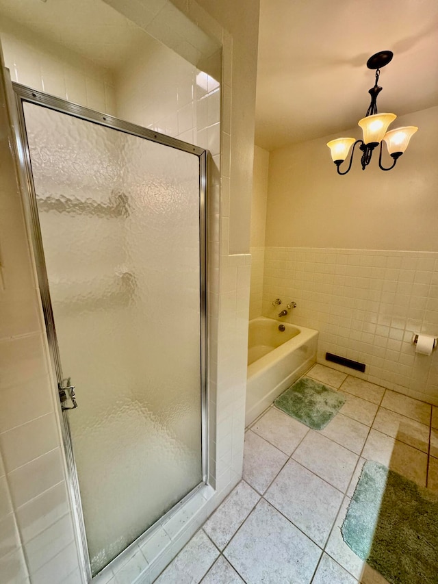 bathroom with shower with separate bathtub, an inviting chandelier, tile patterned floors, and tile walls