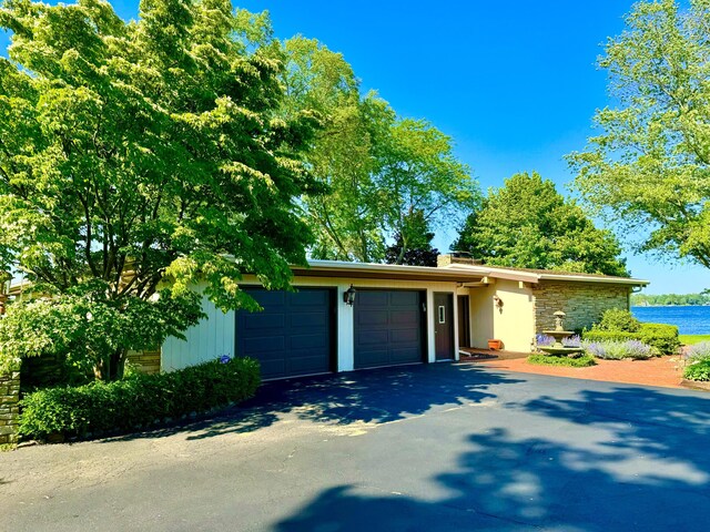 7206 Beechwood Cir, Watervliet, MI 49098 - view of front of house featuring an attached garage, driveway, stone siding, and a water view