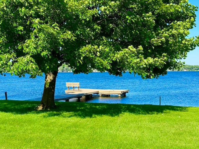 view of dock featuring a lawn and a water view