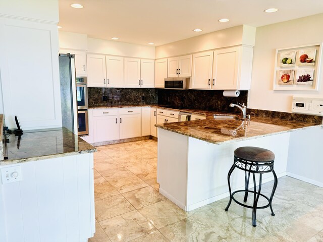 7206 Beechwood Cir, Watervliet, MI 49098 - kitchen with a sink, stainless steel appliances, dark stone countertops, a peninsula, and decorative backsplash