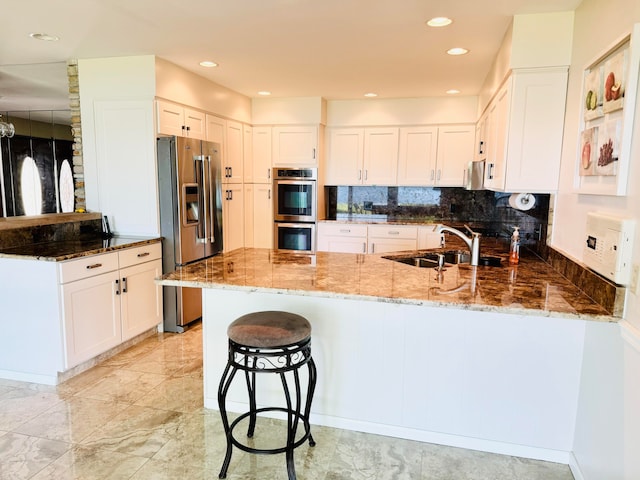 kitchen featuring kitchen peninsula, sink, stainless steel appliances, and stone countertops