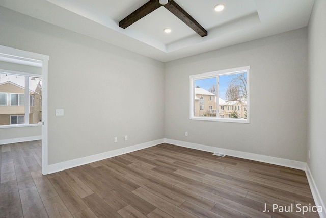 unfurnished room featuring beamed ceiling and hardwood / wood-style flooring