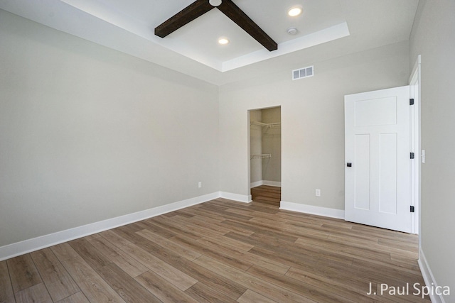 unfurnished bedroom with ceiling fan, wood-type flooring, a walk in closet, and a closet