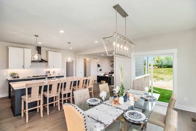 dining space with hardwood / wood-style floors, a notable chandelier, and sink