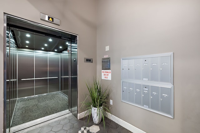 interior space featuring tile patterned floors, mail boxes, a towering ceiling, and elevator