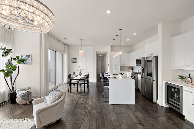 kitchen featuring light countertops, wine cooler, appliances with stainless steel finishes, dark wood-type flooring, and white cabinetry
