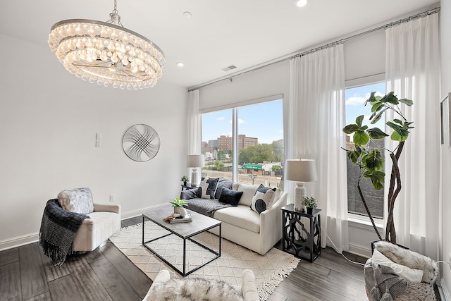 living area featuring baseboards, hardwood / wood-style flooring, a city view, visible vents, and a notable chandelier