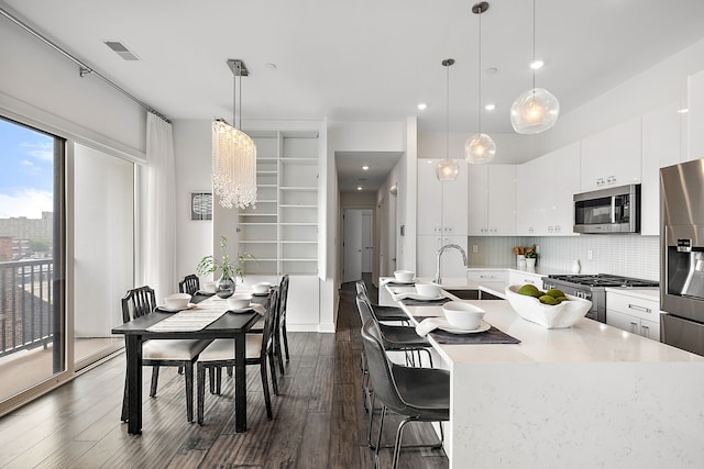 kitchen with dark wood-style flooring, visible vents, stainless steel appliances, tasteful backsplash, and a sink