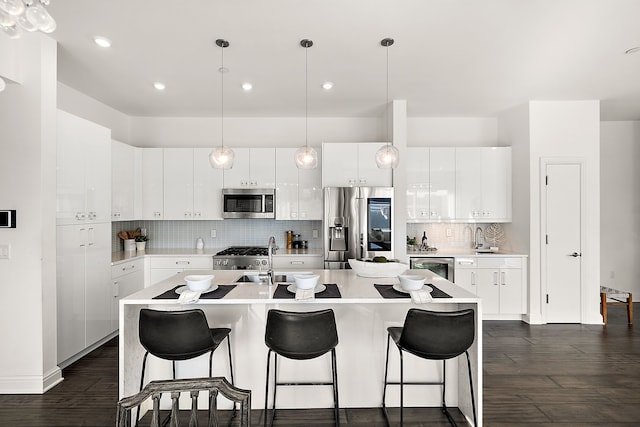 kitchen featuring a center island with sink, a breakfast bar area, light countertops, and appliances with stainless steel finishes