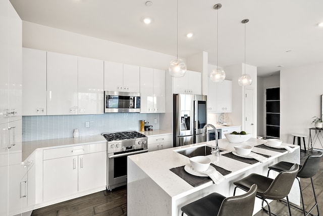 kitchen with stainless steel appliances, dark wood-type flooring, sink, pendant lighting, and white cabinetry