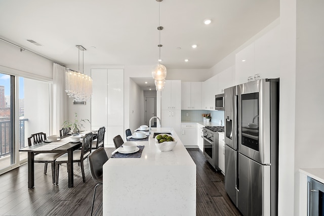 kitchen with appliances with stainless steel finishes, decorative light fixtures, white cabinetry, and a wealth of natural light