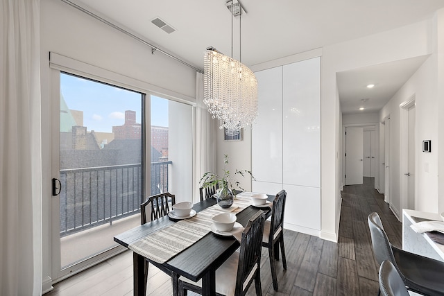 dining room with visible vents, wood finished floors, an inviting chandelier, and a city view