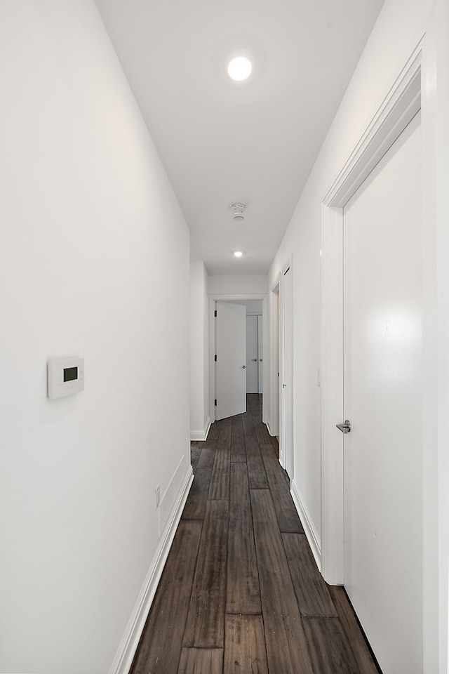 corridor with dark wood-style flooring and baseboards