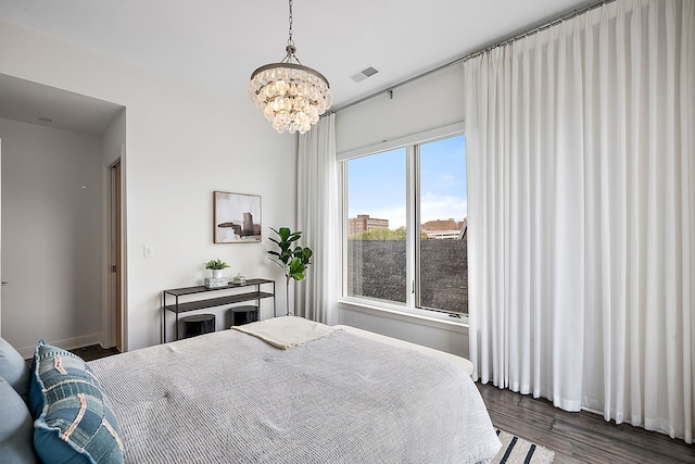 bedroom with dark hardwood / wood-style floors and a notable chandelier