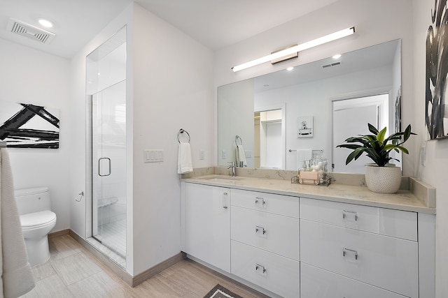 bathroom with hardwood / wood-style flooring, vanity, toilet, and walk in shower