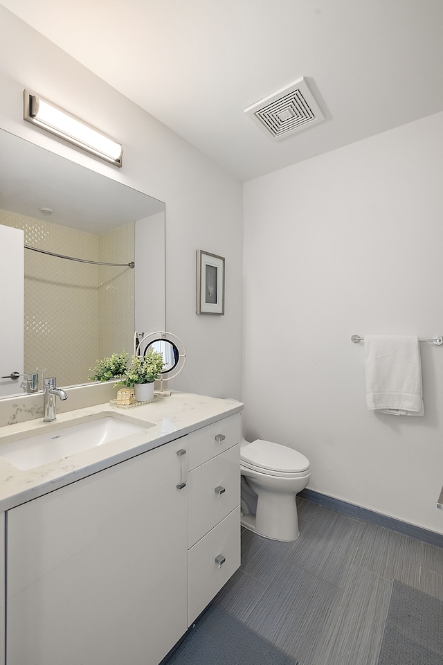 bathroom featuring a tile shower, vanity, and toilet