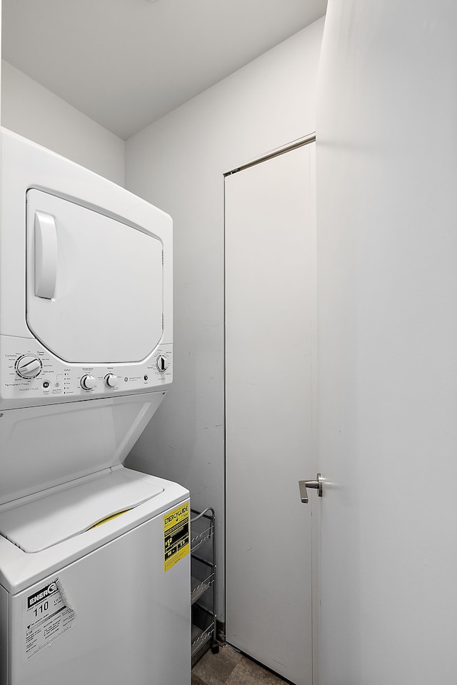 clothes washing area with stacked washer and clothes dryer and laundry area