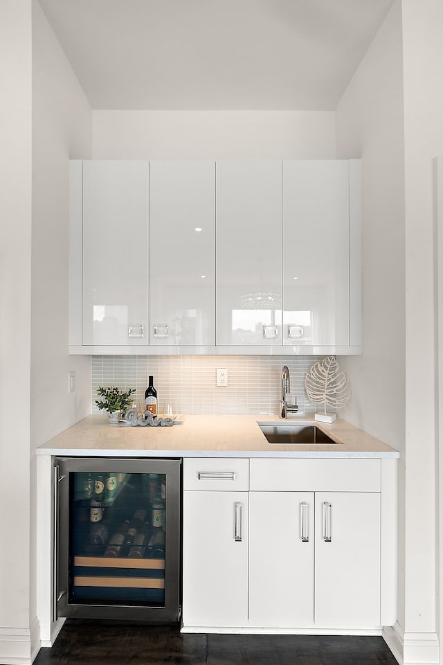 bar with white cabinetry, sink, dark wood-type flooring, beverage cooler, and tasteful backsplash