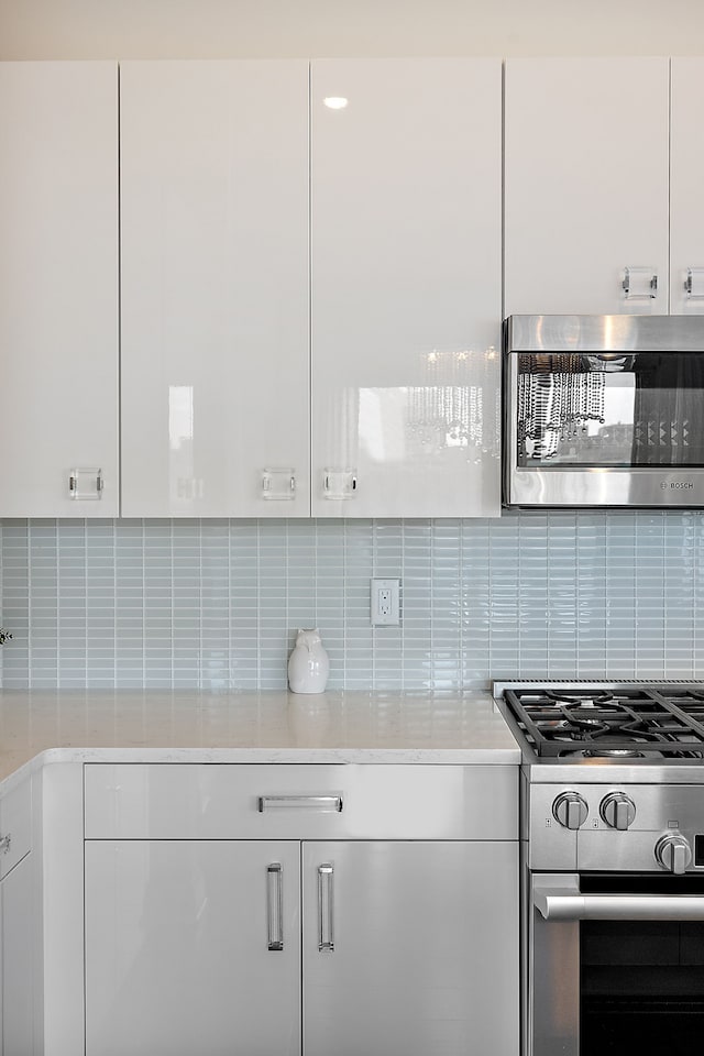 kitchen featuring white cabinets, backsplash, and appliances with stainless steel finishes