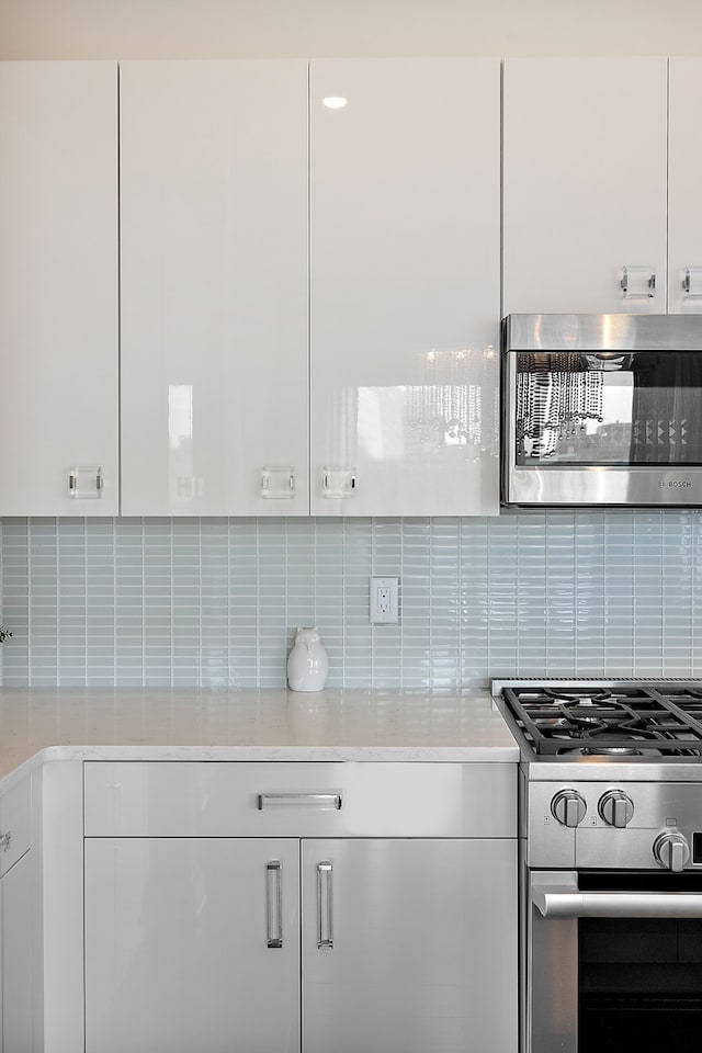 kitchen featuring white cabinetry, light countertops, stainless steel appliances, and backsplash