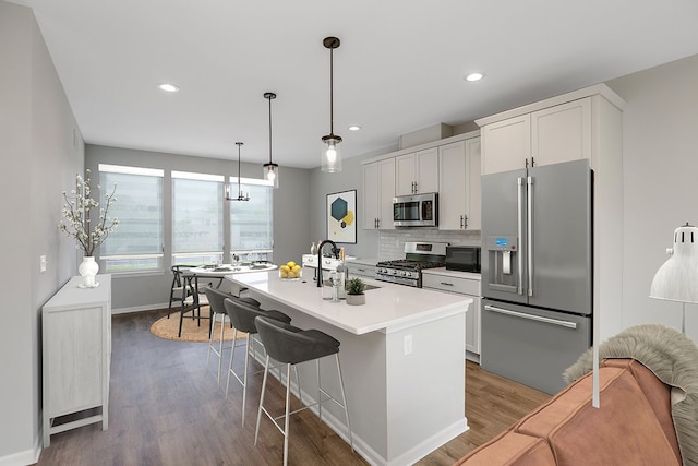 kitchen featuring sink, stainless steel appliances, tasteful backsplash, a center island with sink, and white cabinets