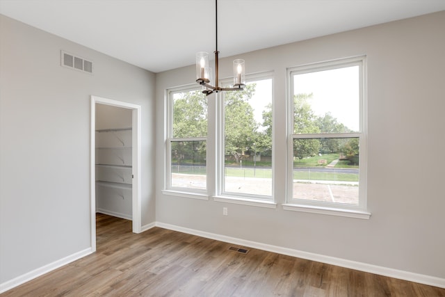 unfurnished dining area featuring a chandelier and light wood-type flooring