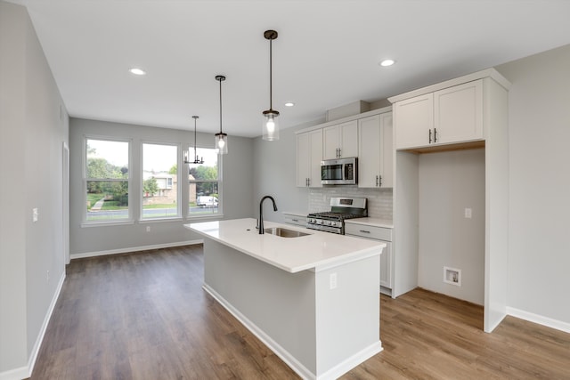 kitchen with pendant lighting, a center island with sink, sink, appliances with stainless steel finishes, and white cabinetry