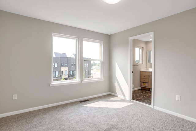 unfurnished bedroom with dark carpet and ensuite bath