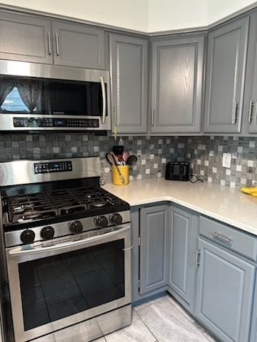 kitchen featuring gray cabinetry, stainless steel appliances, and tasteful backsplash