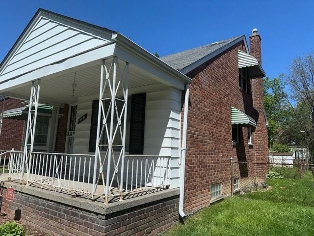 14141 Rossini Dr, Detroit, MI 48205 - view of home's exterior featuring a porch, brick siding, and a chimney