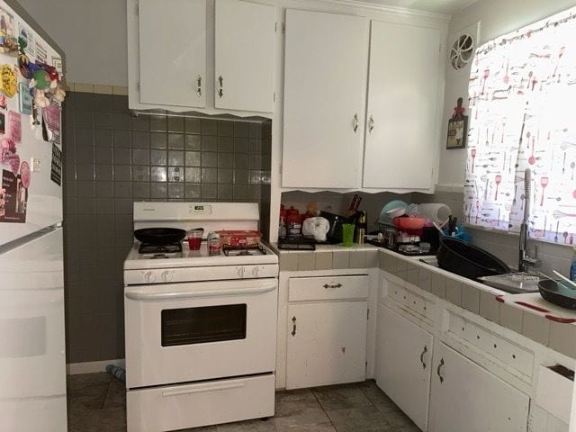 kitchen with tile countertops, white cabinetry, dark tile patterned flooring, and white appliances