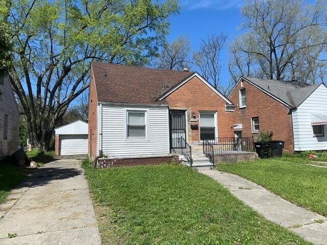 bungalow-style house with an outbuilding, a front yard, and a garage