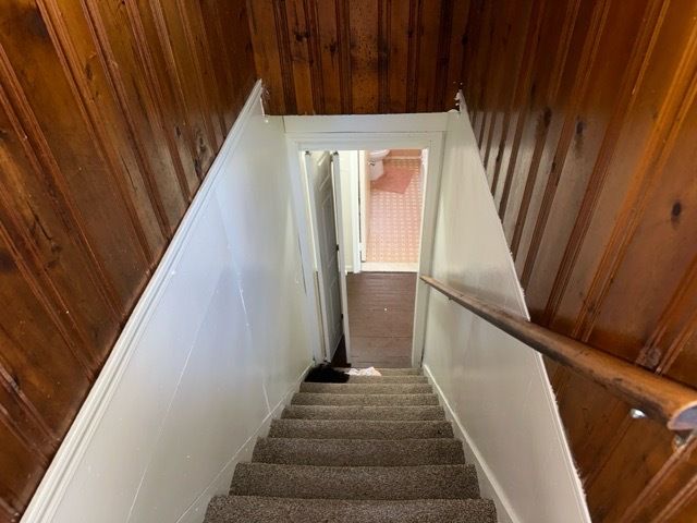 stairs with wood walls and carpet