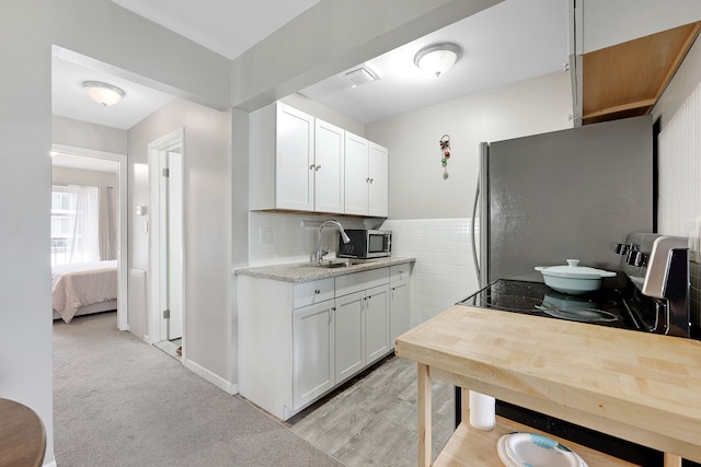 kitchen featuring stainless steel appliances, white cabinetry, sink, and light colored carpet