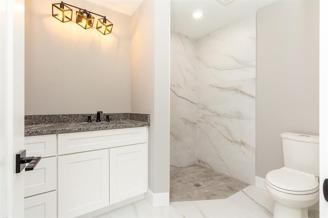 bathroom with vanity, toilet, and tiled shower