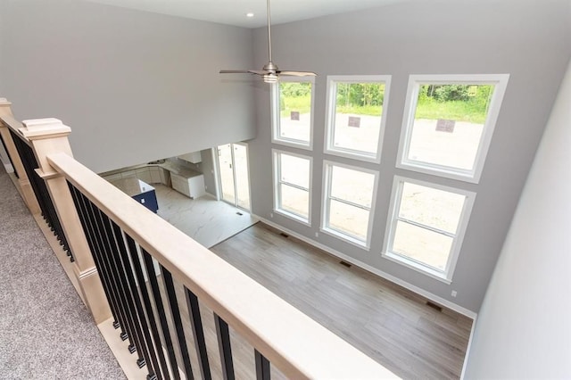 stairs featuring a high ceiling, hardwood / wood-style flooring, plenty of natural light, and ceiling fan